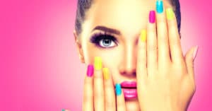 Image of girl with colorful nail polish and her hands on her face.