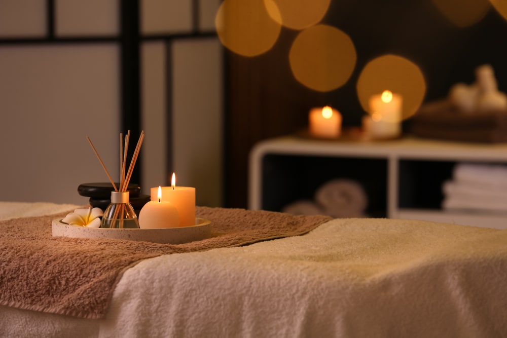 Burning candles and aromatic reed freshener on a table in spa salon