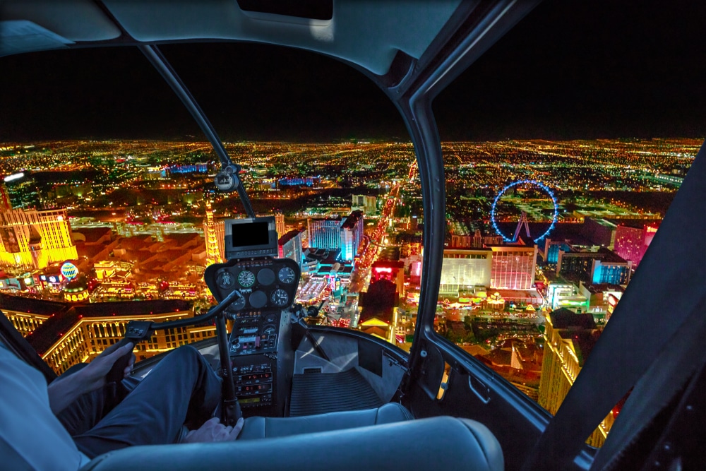 Helicopter interior on Las Vegas buildings and skyscrapers of downtown with illuminated casino hotels at night.