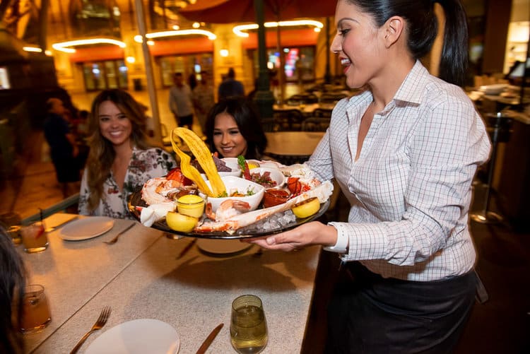 HEXX bar waitress brining out seafood platter to ladies 