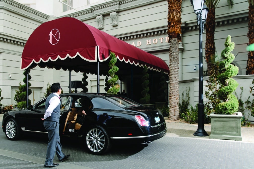 A valet opening a car door outside a hotel