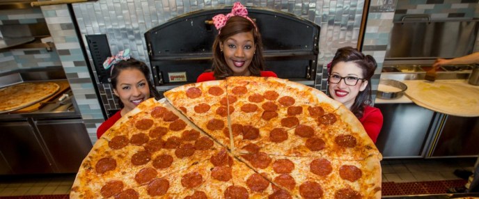 pin-up employees holding up massive pepperoni pizza 