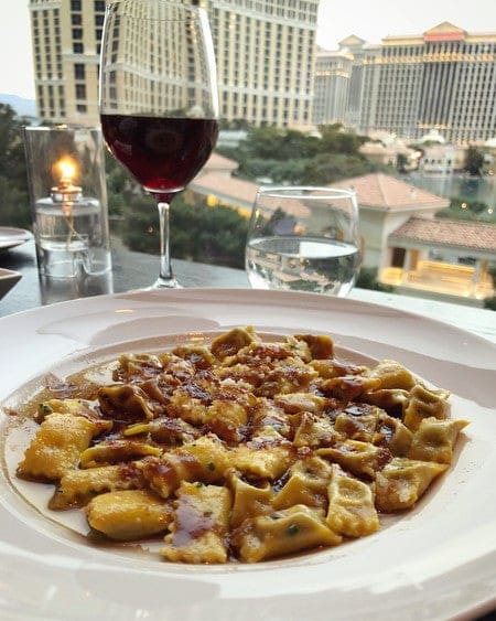 dish of scarpetta pasta and glass of wine with a view of las vegas strip 