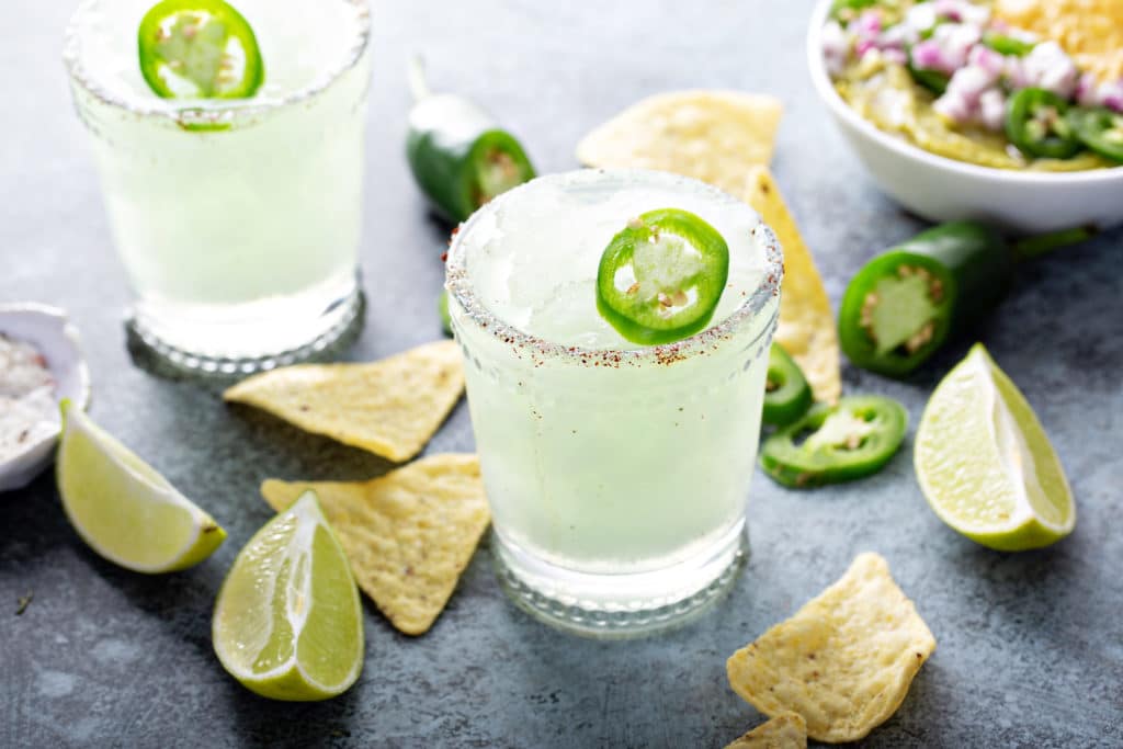 tequila margaritas surrounded by lime and chips 