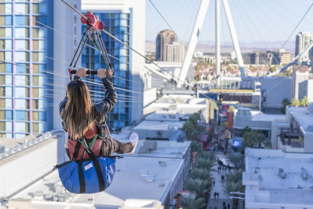 girl riding the zipline with bag underneath