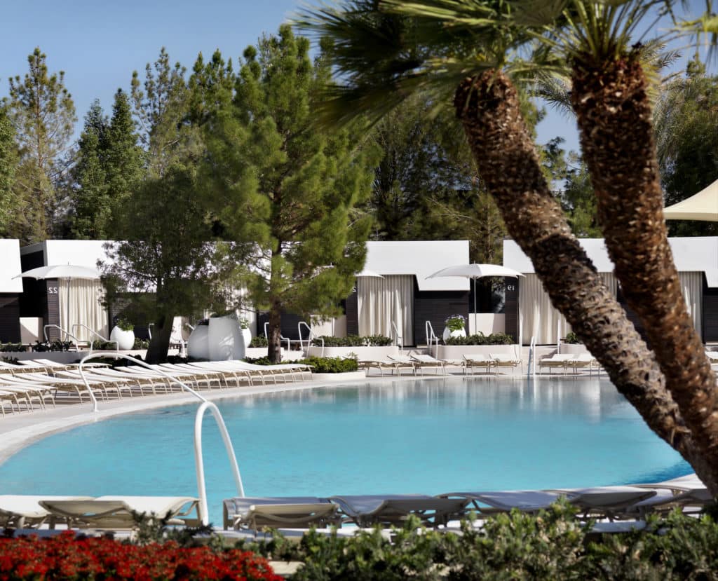 white cabanas around the ARIA pool set with palm trees and greenery