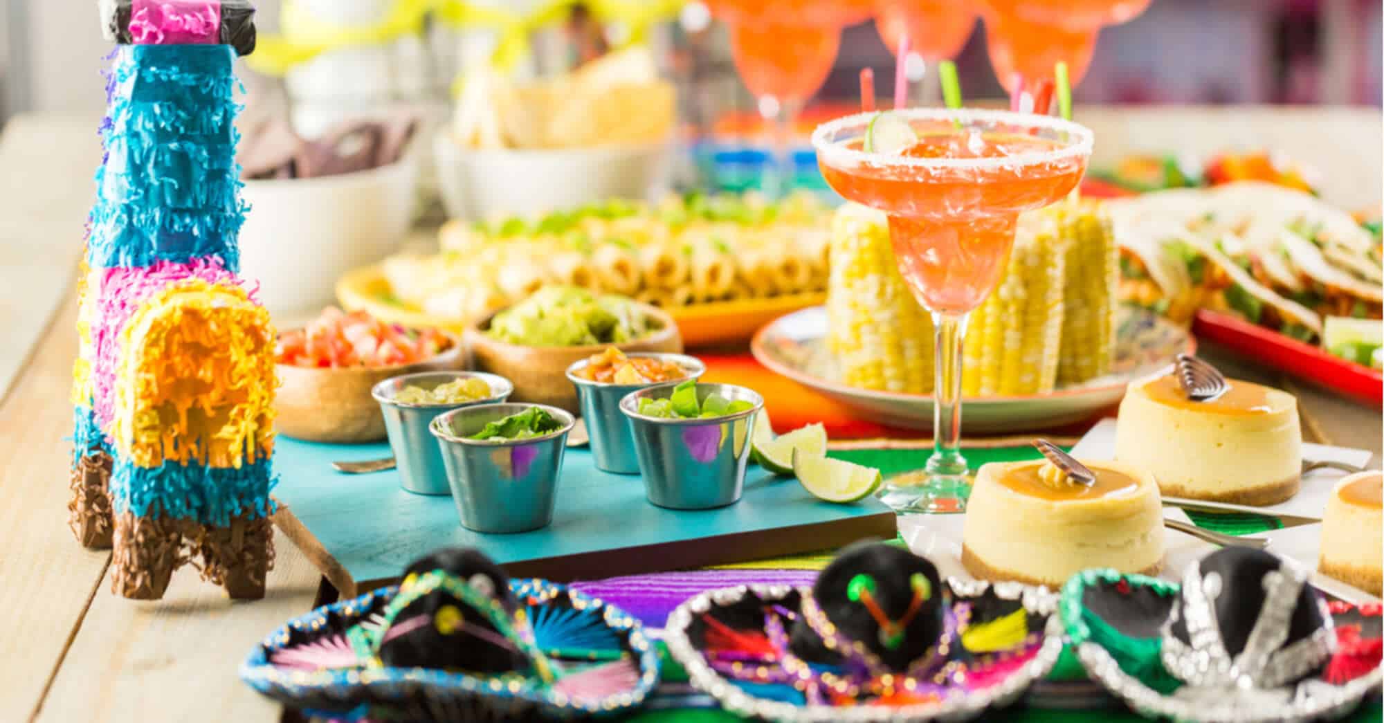 colorful decorations, food and drinks next to a piñata on a table