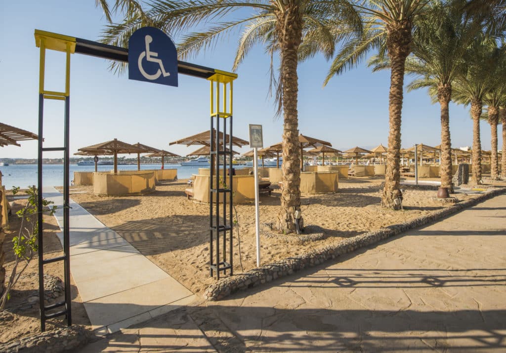 entrance to a tropical beach with an entryway with a handicap sign and a flat walkway
