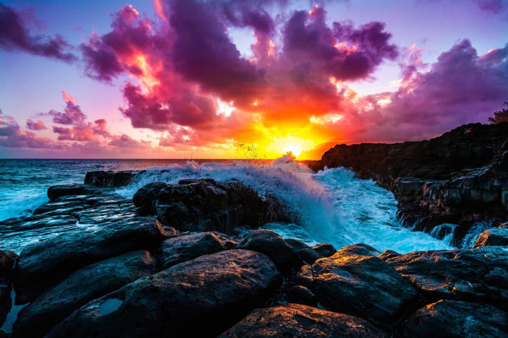 a multicolored sunset over rocks and the sea in Kauai Hawai'i