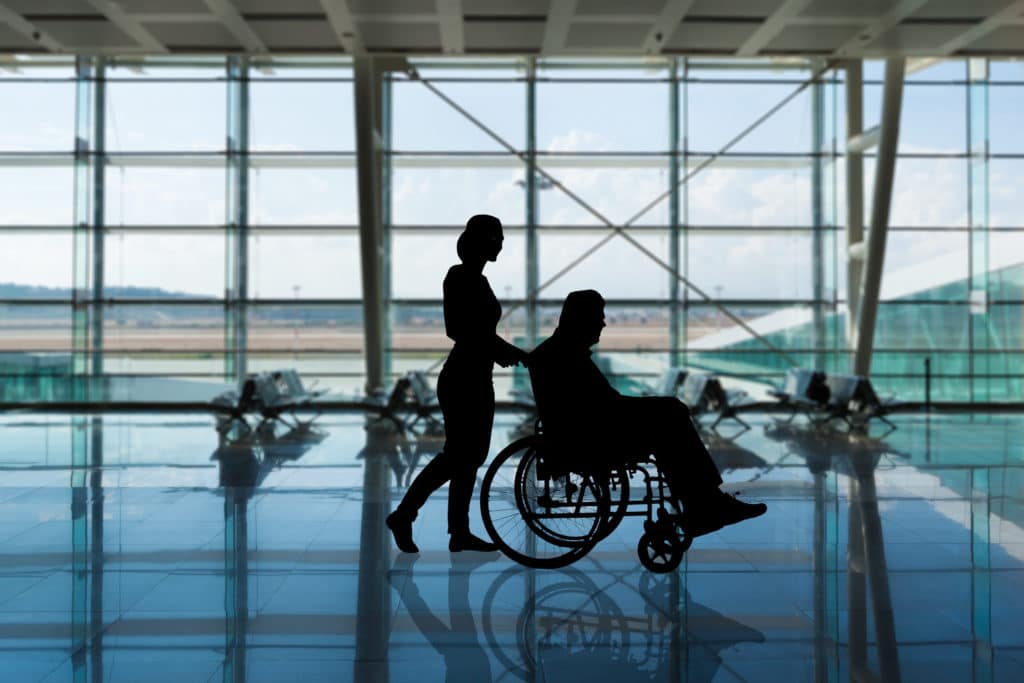 Woman pushing an older man in a wheelchair at an airport