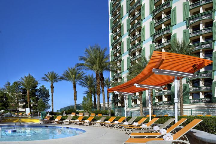 pool at The Orleans Las Vegas with orange umbrellas and loungers with palm trees in the background