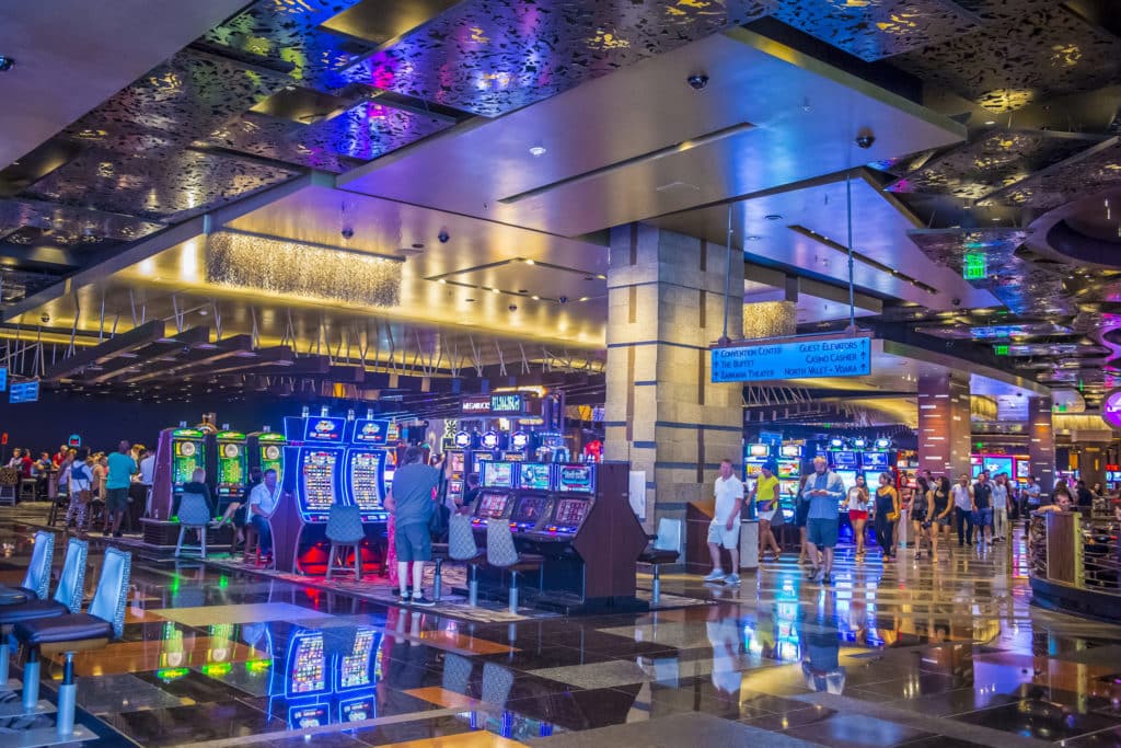people playing on neon-lit slot machines inside a casino
