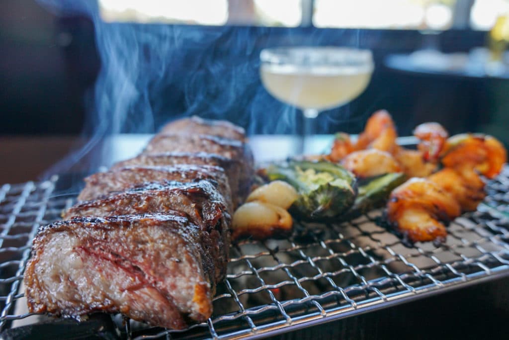 a sizzling rack with steak, shrimp and vegetables to complement a small margarita in the background