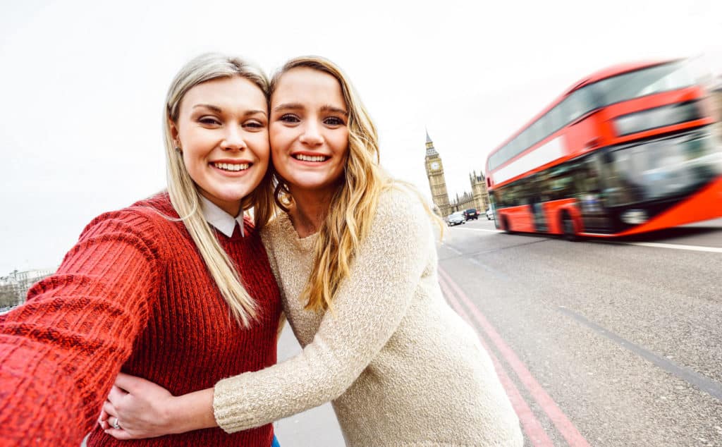 two women taking a selfie in London next to a moving bus