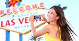 woman taking a photo in front of the Las Vegas sign as part of the Las Vegas photos checklist