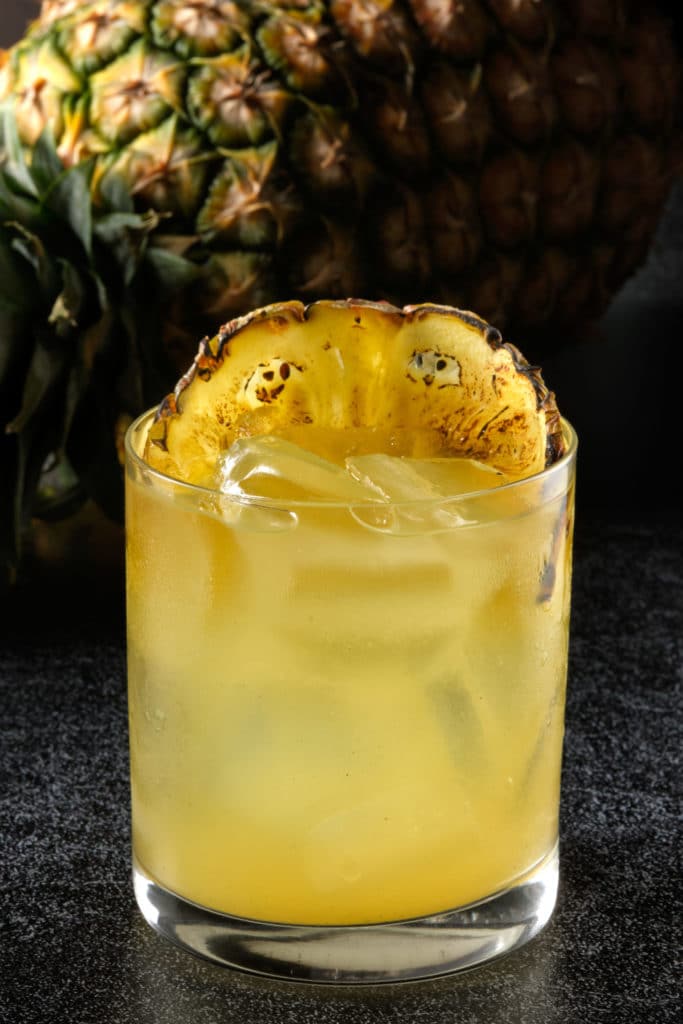 a light yellow cocktail with pineapple garnish