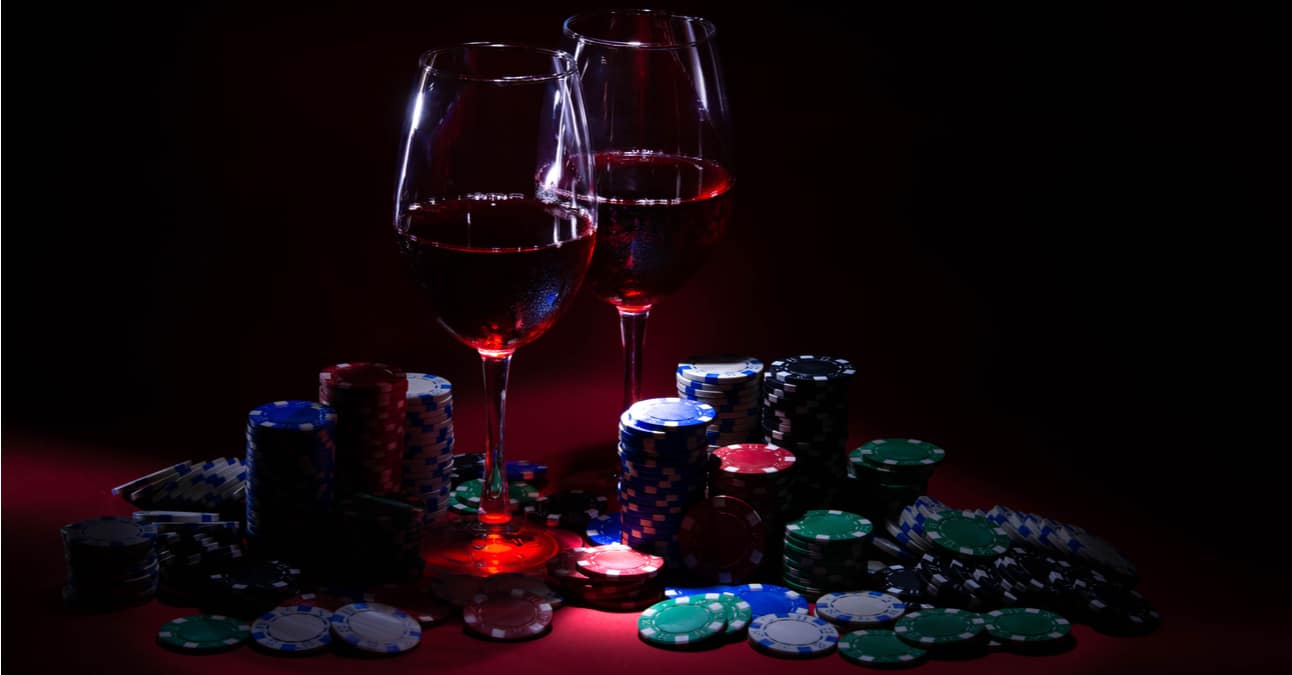 two glasses with red wine sitting among poker chips