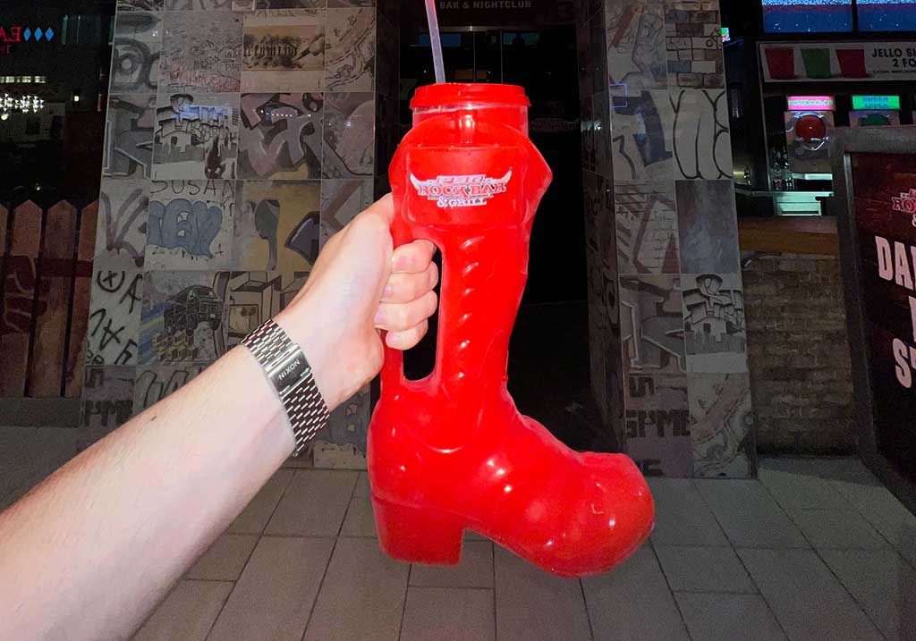 A woman holding a boot full of booze