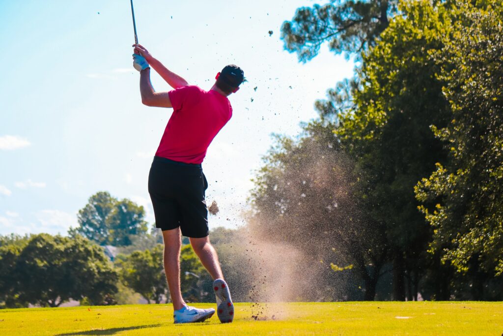 A male golfer swinging at the ground