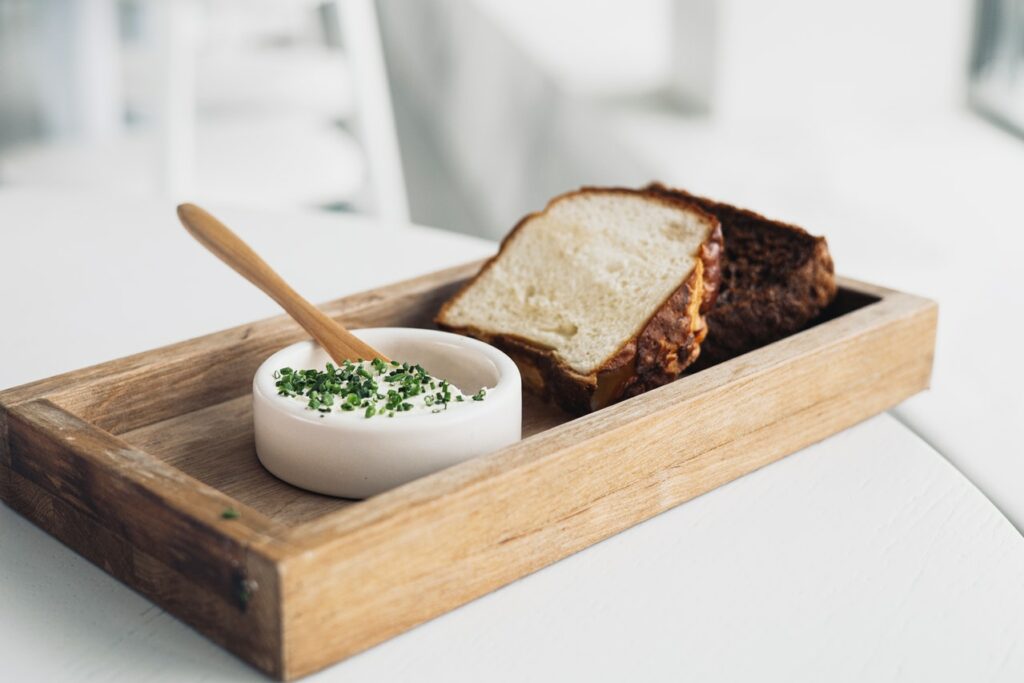 Photograph of delicious looking foie gras served with crusty bread on a rustic wooden tray.