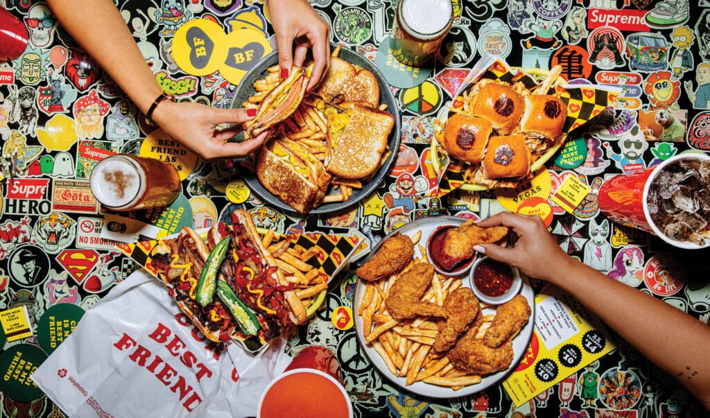 hands reaching for food on a table with stickers