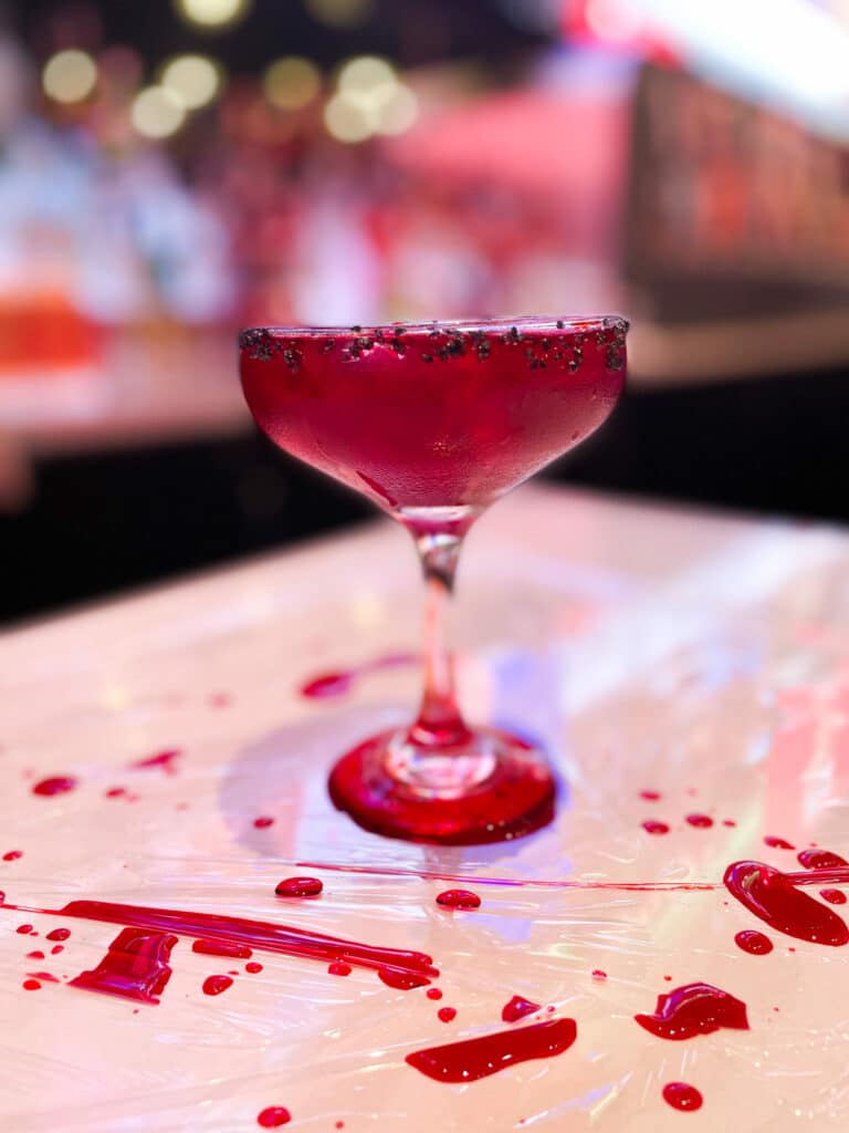 a red cocktail on a plastic wrap table with red liquid