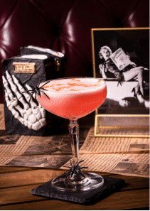 a pink cocktail with skeleton hands