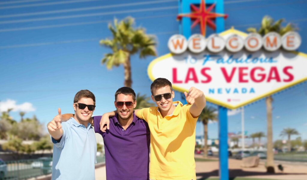 Three men in sunglasses standing in front of the Las Vegas sign