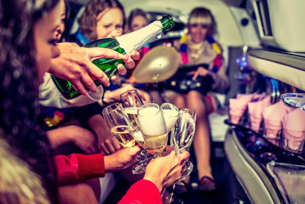 Women pouring champagne in a party bus for a Vegas bachelorette party.