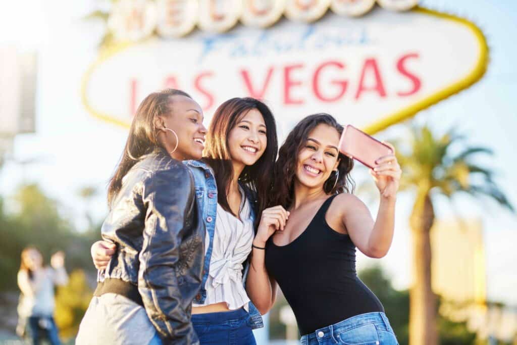 Three women from a Vegas bachelorette party taking a selfie in from of the Las Vegas sign.