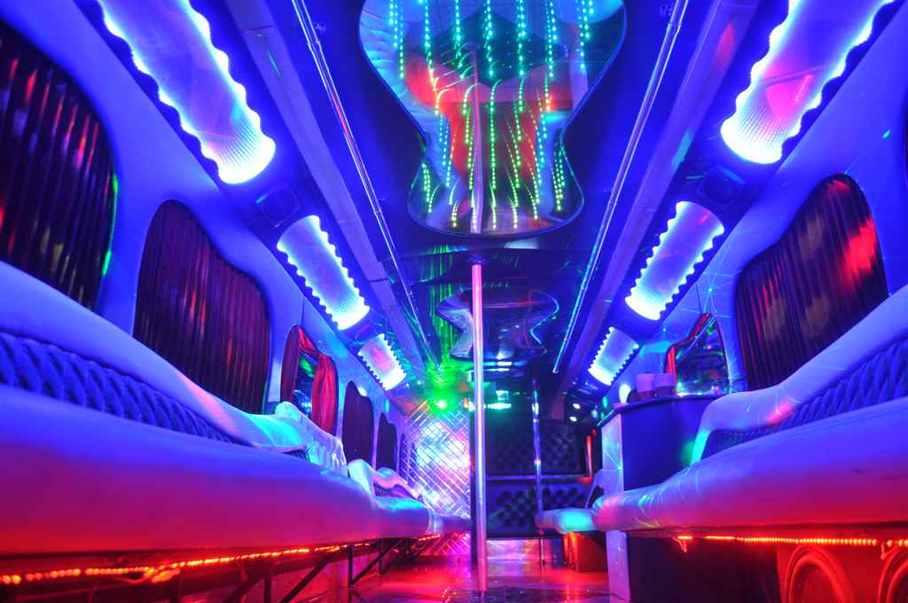 Colorful lights inside a Las Vegas party bus illuminating a stripper pole