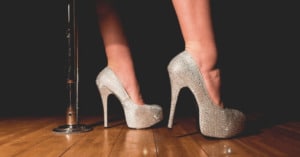 A woman's feet in sparkly high heels next to a stripper pole